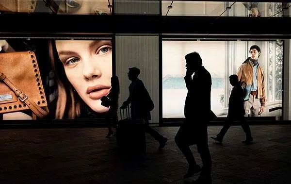 People walking pass large window prints