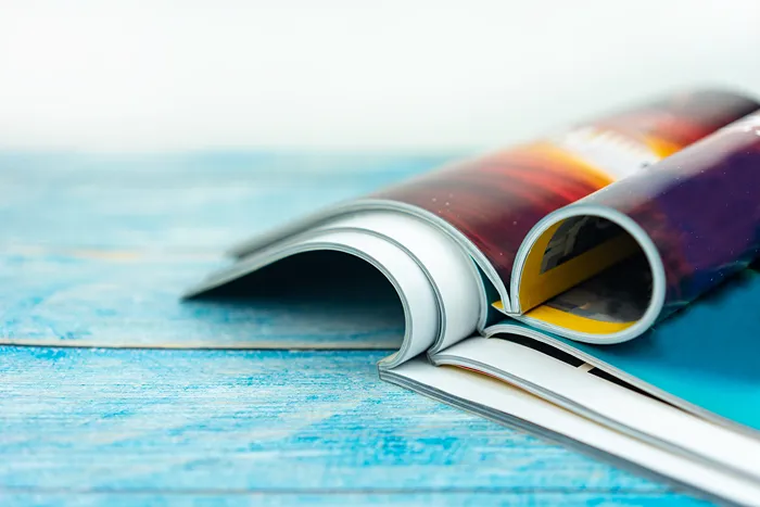 Three magazines open on a blue table