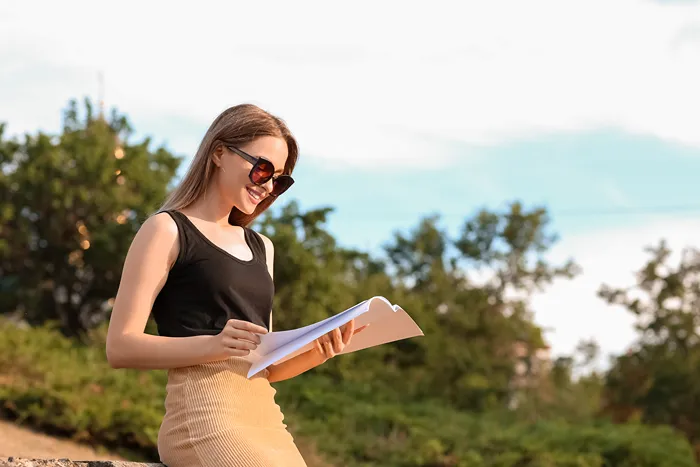 Woman outside in the sun reading a catalog