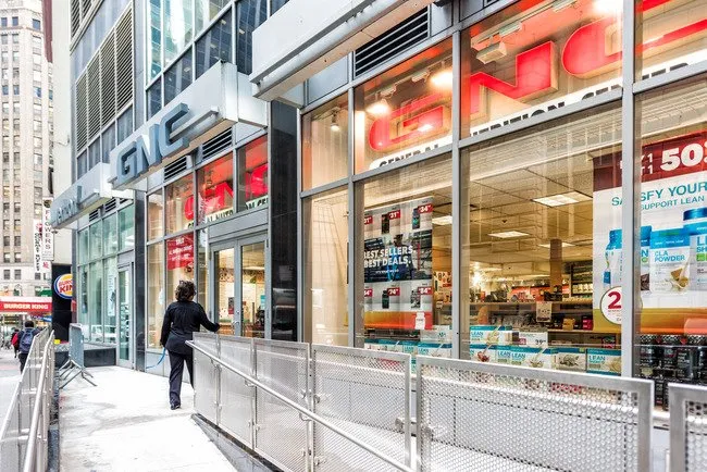 Woman walking down the street in NYC going to a GNC store with Vinyl Window and Wall Graphics