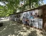 Wheat paste posters on a wall next to a sidewalk in NYC